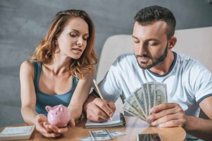 How to Manage Money, Couple budgeting their money at the table as they begin to manage their money better and stop living paycheck to paycheck.