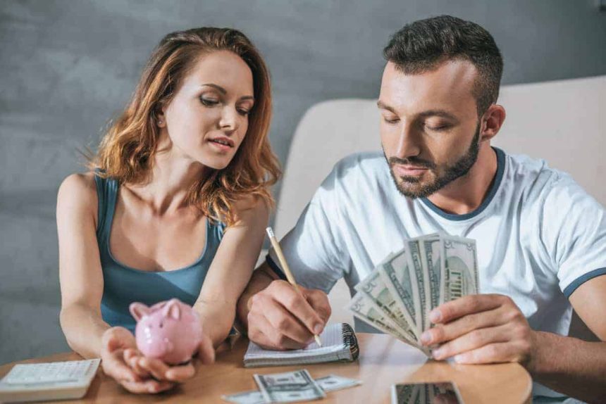 How to Manage Money, Couple budgeting their money at the table as they begin to manage their money better and stop living paycheck to paycheck.
